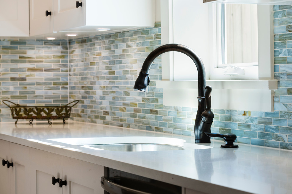 Inspiration for a mid-sized coastal l-shaped light wood floor open concept kitchen remodel in Vancouver with an undermount sink, shaker cabinets, white cabinets, quartz countertops, blue backsplash, glass sheet backsplash, stainless steel appliances and an island