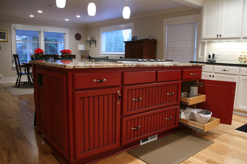 Eat-in kitchen - mid-sized cottage l-shaped light wood floor eat-in kitchen idea in Portland with a drop-in sink, beaded inset cabinets, red cabinets, granite countertops, stainless steel appliances, an island, white backsplash and subway tile backsplash