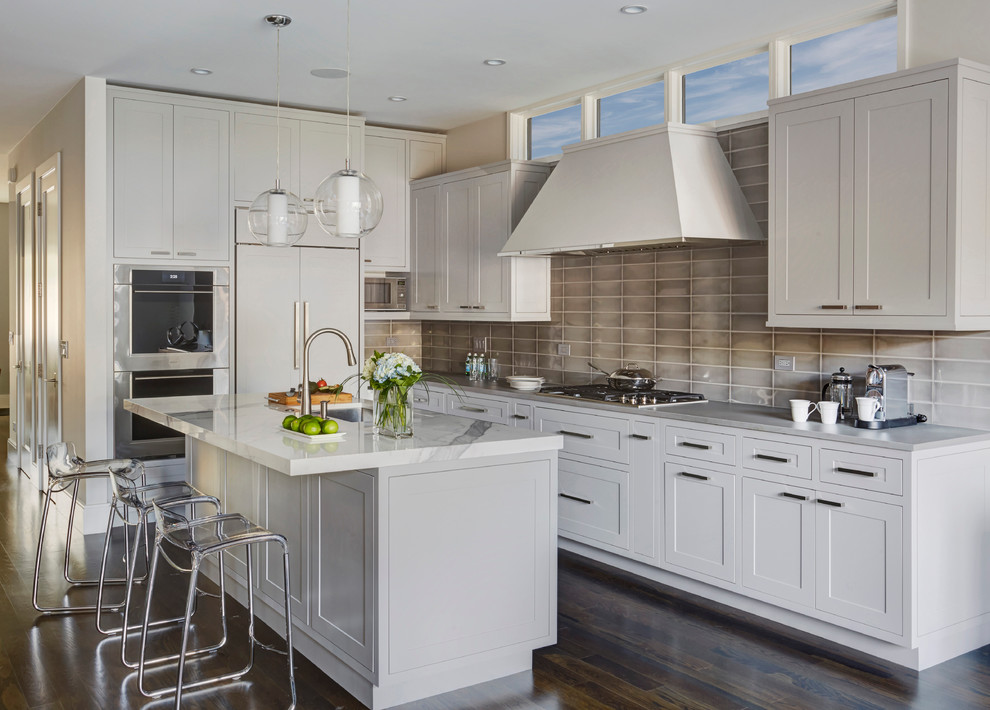 Mid-sized transitional l-shaped dark wood floor eat-in kitchen photo in Chicago with an undermount sink, shaker cabinets, gray cabinets, gray backsplash, stainless steel appliances, an island, onyx countertops and glass tile backsplash