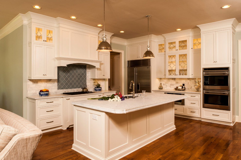 Inspiration for a mid-sized timeless l-shaped medium tone wood floor open concept kitchen remodel in Raleigh with a single-bowl sink, beaded inset cabinets, white cabinets, marble countertops, white backsplash, subway tile backsplash, stainless steel appliances and an island