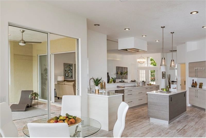 Photo of a medium sized contemporary l-shaped open plan kitchen in Tampa with a single-bowl sink, flat-panel cabinets, beige cabinets, engineered stone countertops, white splashback, stone slab splashback, stainless steel appliances, porcelain flooring, an island and multi-coloured floors.