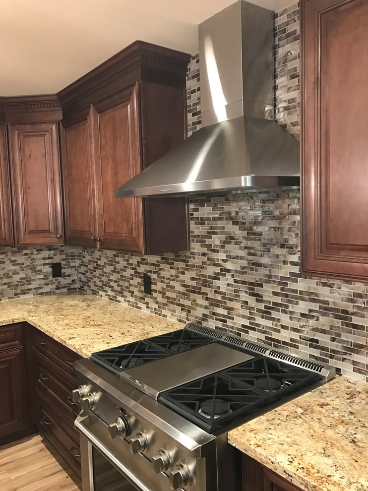 Exempel på ett mellanstort modernt kök, med en dubbel diskho, bruna skåp, granitbänkskiva, grått stänkskydd, stänkskydd i mosaik, rostfria vitvaror, vinylgolv, en köksö och brunt golv