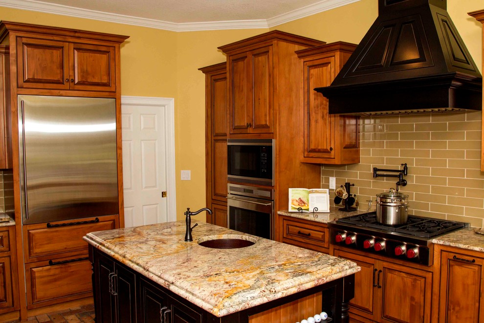 Foto på ett mellanstort vintage kök, med en undermonterad diskho, luckor med profilerade fronter, skåp i mellenmörkt trä, granitbänkskiva, gult stänkskydd, stänkskydd i tunnelbanekakel, rostfria vitvaror, tegelgolv och en köksö