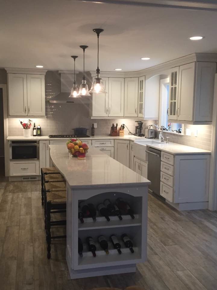Inspiration for a large farmhouse u-shaped open plan kitchen in Boston with a belfast sink, recessed-panel cabinets, white cabinets, engineered stone countertops, grey splashback, metro tiled splashback, stainless steel appliances, porcelain flooring and an island.