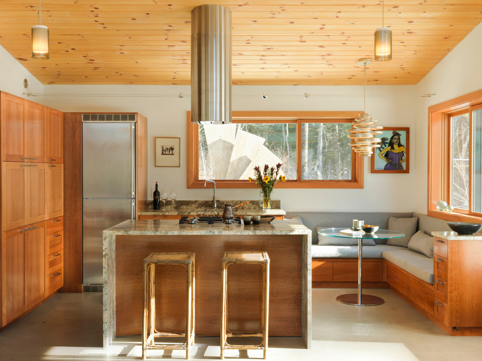 Idées déco pour une cuisine américaine moderne en L et bois clair de taille moyenne avec îlot, un évier encastré, un électroménager en acier inoxydable, un placard à porte shaker, un plan de travail en granite, une crédence grise, une crédence en dalle de pierre, sol en béton ciré et un sol gris.