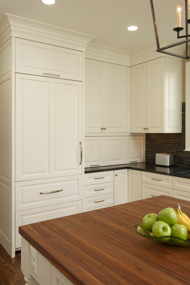 Example of a large classic l-shaped medium tone wood floor eat-in kitchen design in DC Metro with an undermount sink, beaded inset cabinets, white cabinets, wood countertops, gray backsplash, mosaic tile backsplash, paneled appliances and an island
