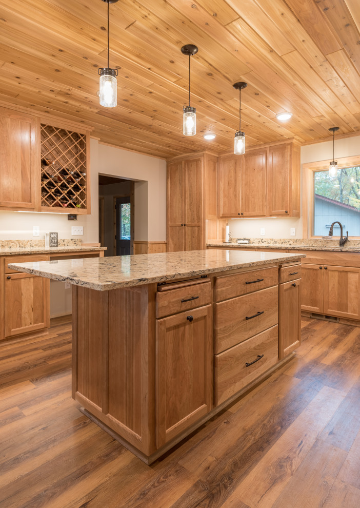Cette image montre une grande cuisine américaine chalet en bois clair avec un placard avec porte à panneau encastré, un plan de travail en quartz modifié, îlot, un plan de travail multicolore et un plafond en bois.
