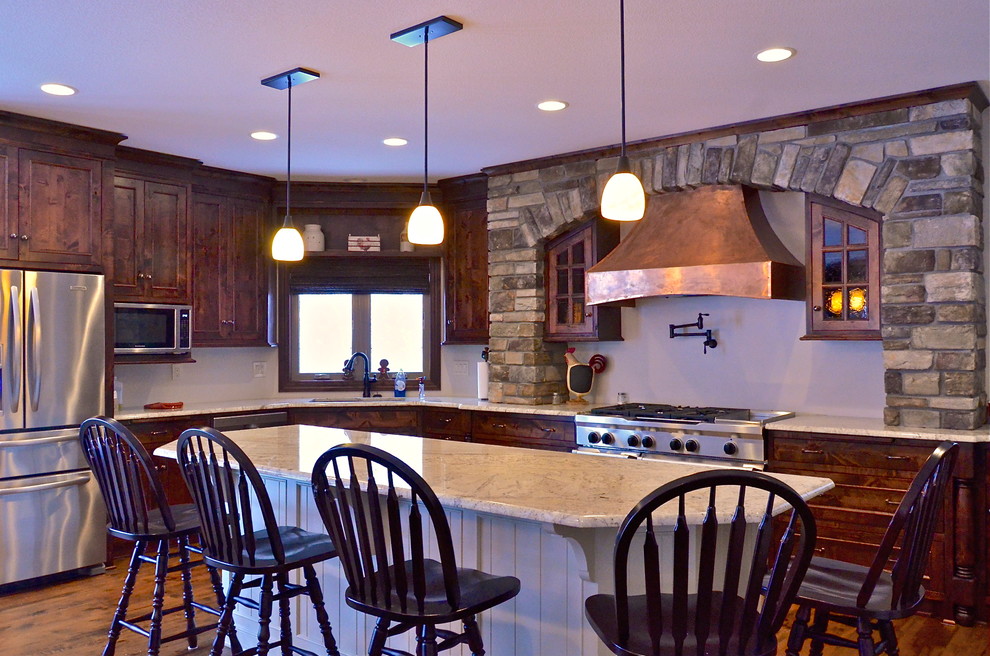 Exempel på ett rustikt l-kök, med en undermonterad diskho, luckor med profilerade fronter, vita skåp, granitbänkskiva, rostfria vitvaror, ljust trägolv och en köksö