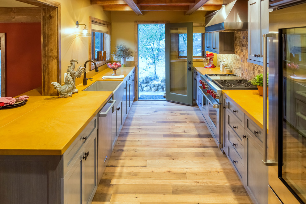 Mid-sized mountain style galley light wood floor open concept kitchen photo in Los Angeles with a farmhouse sink, shaker cabinets, gray cabinets, limestone countertops, multicolored backsplash, mosaic tile backsplash and stainless steel appliances