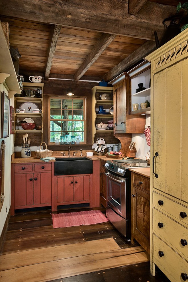 Foto på ett litet rustikt l-kök, med en rustik diskho, röda skåp, integrerade vitvaror och mörkt trägolv