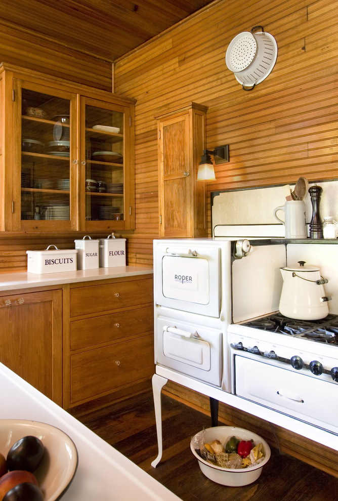 Inspiration for a shabby-chic style kitchen remodel in Minneapolis with glass-front cabinets, medium tone wood cabinets and white appliances
