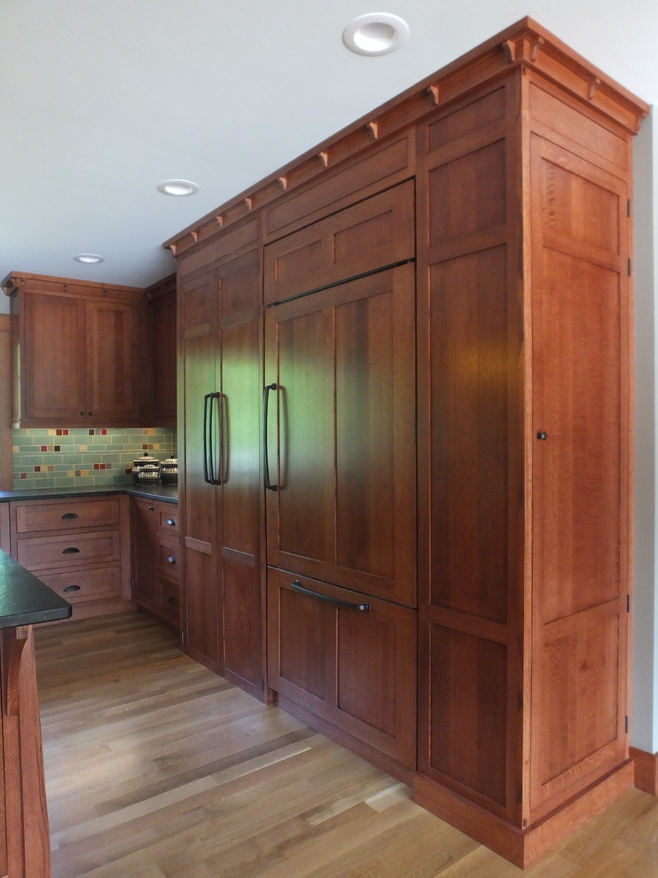 Exemple d'une cuisine craftsman en bois brun avec un placard avec porte à panneau encastré, un plan de travail en granite, une crédence verte, une crédence en céramique et plan de travail noir.