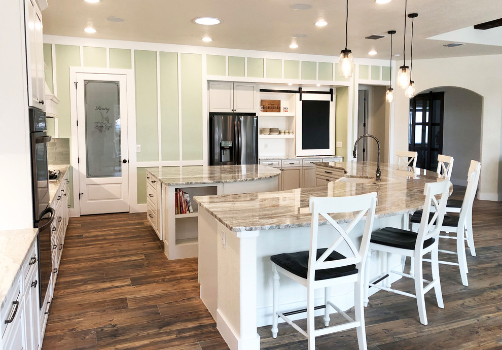 Bild på ett mycket stort lantligt flerfärgad flerfärgat kök, med en rustik diskho, luckor med upphöjd panel, vita skåp, granitbänkskiva, grönt stänkskydd, stänkskydd i glaskakel, rostfria vitvaror, klinkergolv i keramik, flera köksöar och brunt golv