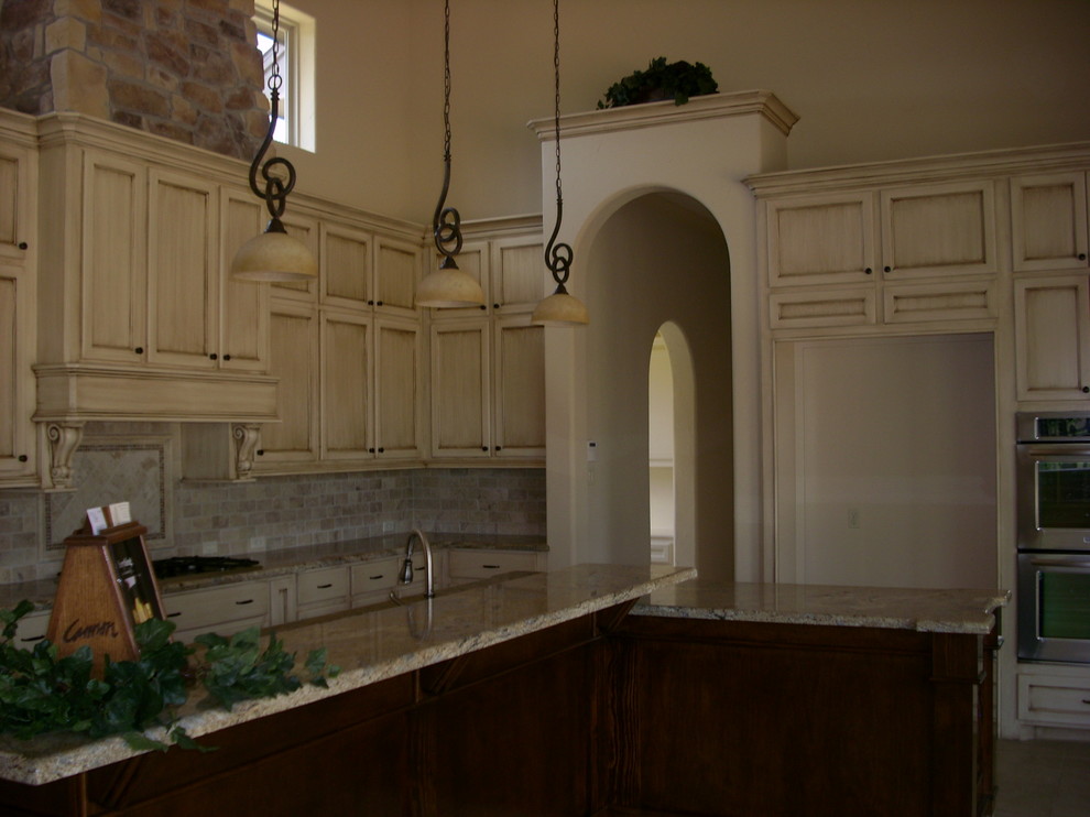 Inredning av ett klassiskt kök, med en undermonterad diskho, skåp i shakerstil, skåp i slitet trä, granitbänkskiva, flerfärgad stänkskydd, stänkskydd i tunnelbanekakel och rostfria vitvaror