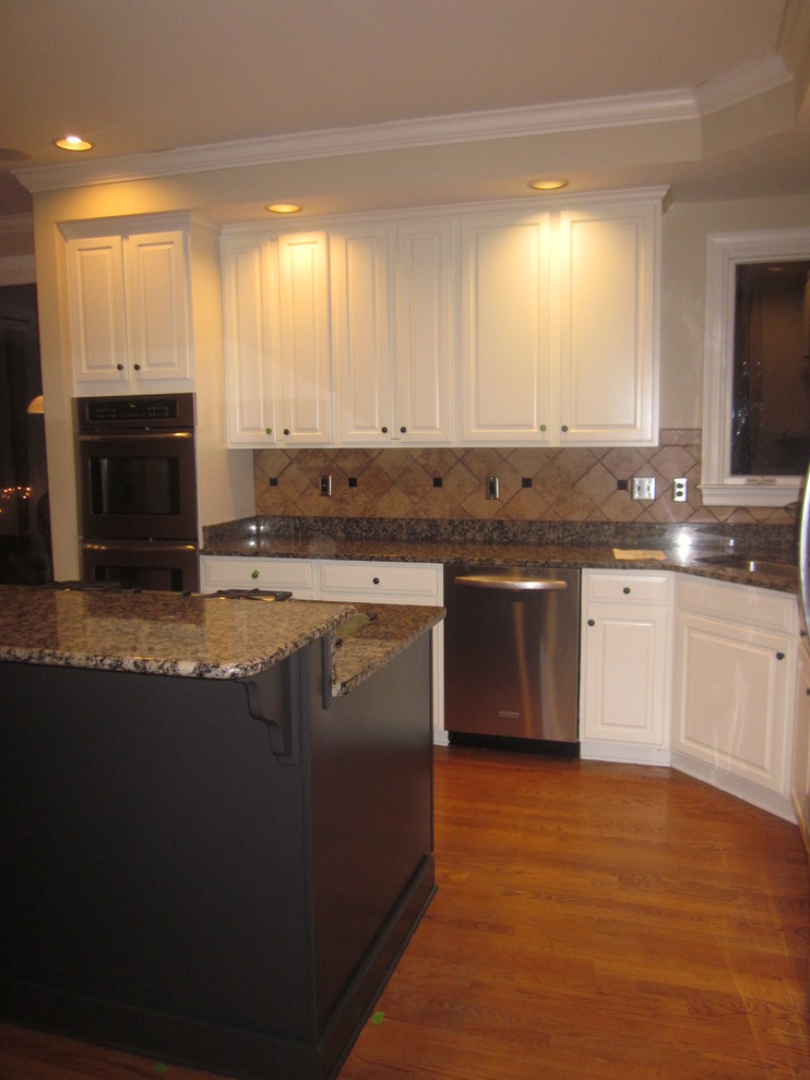 Modern inredning av ett mellanstort kök, med en enkel diskho, luckor med upphöjd panel, vita skåp, granitbänkskiva, orange stänkskydd, stänkskydd i terrakottakakel, rostfria vitvaror, mellanmörkt trägolv och en köksö