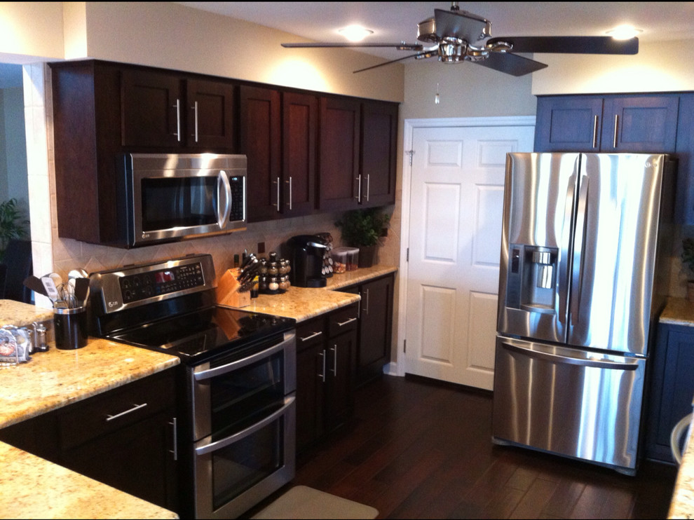 Exempel på ett mellanstort modernt kök, med skåp i shakerstil, skåp i mörkt trä, rostfria vitvaror, granitbänkskiva, beige stänkskydd, stänkskydd i porslinskakel, mörkt trägolv och brunt golv