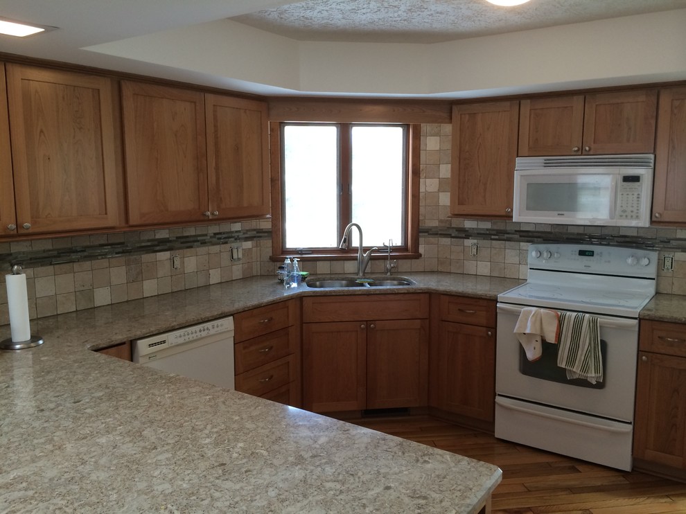 Example of a mid-sized trendy u-shaped medium tone wood floor and beige floor eat-in kitchen design in Denver with an undermount sink, shaker cabinets, light wood cabinets, granite countertops, beige backsplash, porcelain backsplash, white appliances and a peninsula