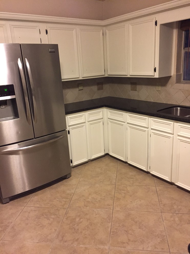 This is an example of a medium sized traditional u-shaped enclosed kitchen in Houston with white cabinets, a double-bowl sink, beaded cabinets, tile countertops, beige splashback, stone tiled splashback, stainless steel appliances, porcelain flooring and no island.