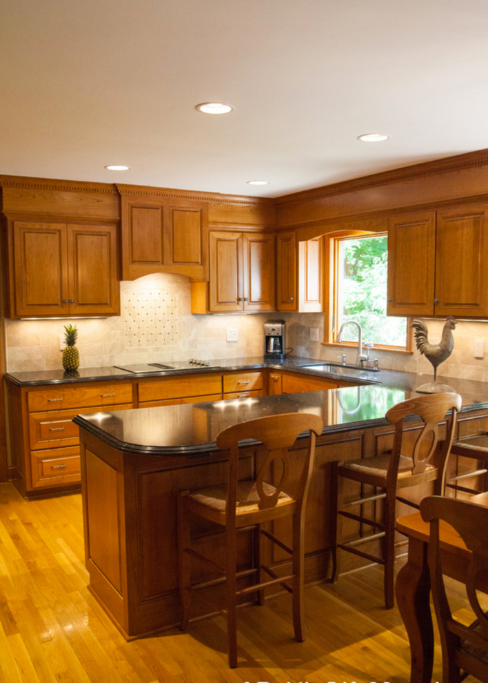 Bild på ett stort vintage kök, med en undermonterad diskho, luckor med upphöjd panel, skåp i mellenmörkt trä, bänkskiva i kvartsit, beige stänkskydd, stänkskydd i keramik, rostfria vitvaror och ljust trägolv