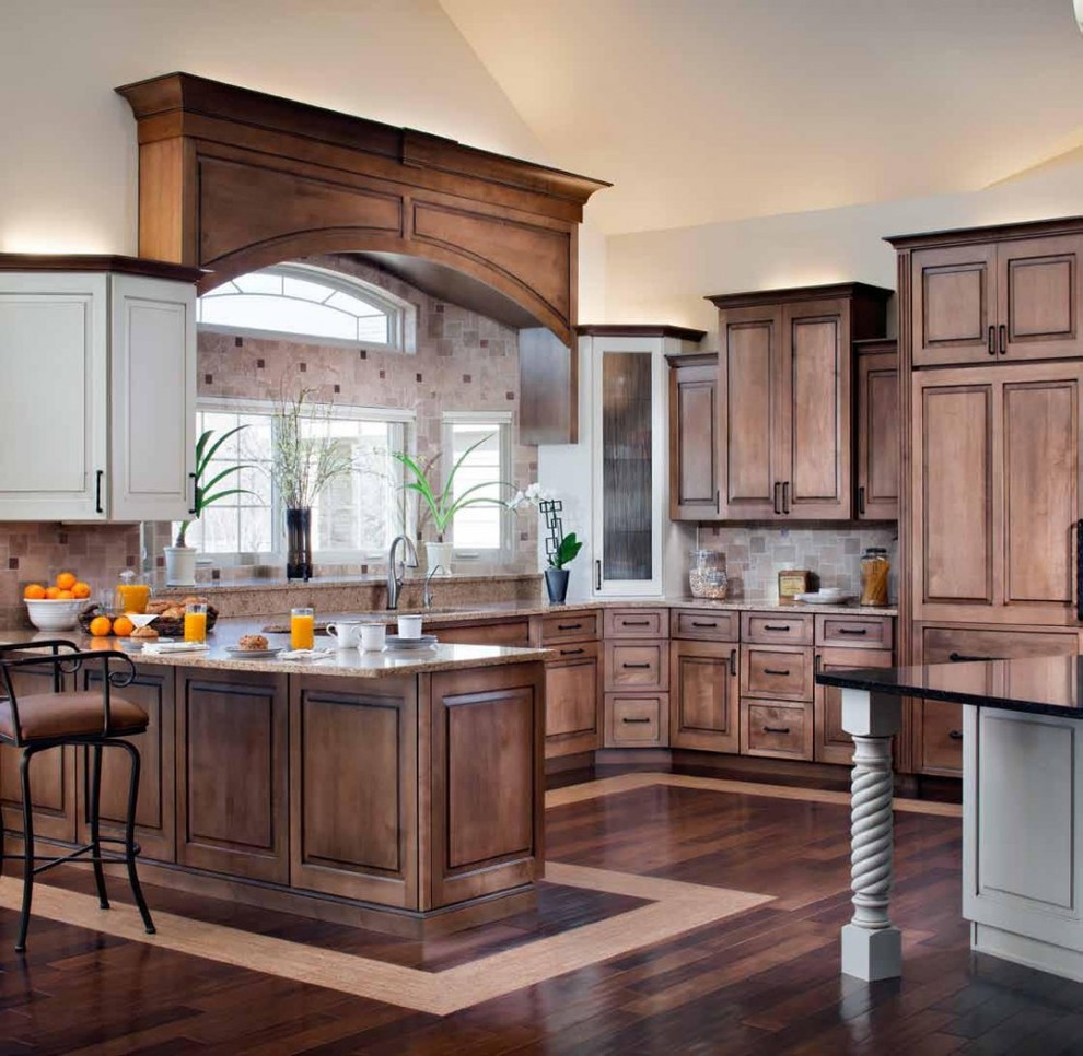 Modern inredning av ett mycket stort brun brunt kök, med en undermonterad diskho, luckor med upphöjd panel, bruna skåp, bänkskiva i kvarts, brunt stänkskydd, stänkskydd i travertin, integrerade vitvaror, mörkt trägolv, en köksö och brunt golv