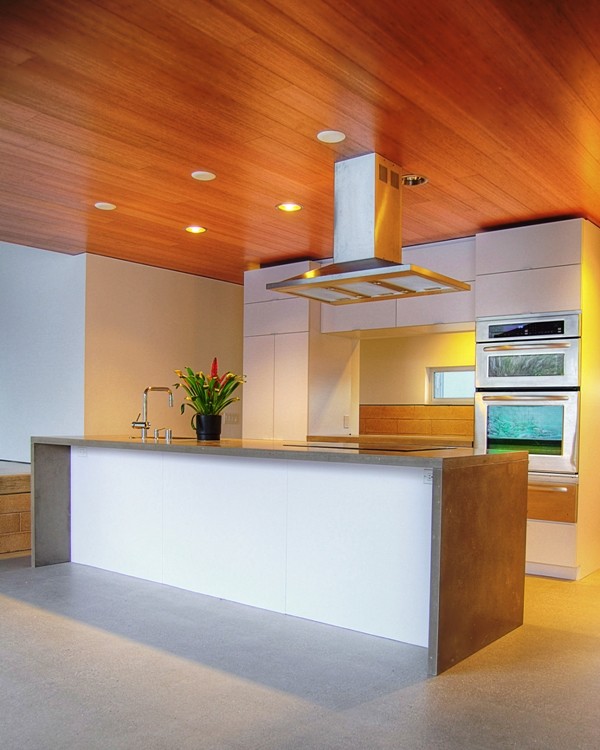 Exempel på ett mellanstort industriellt kök, med en undermonterad diskho, släta luckor, vita skåp, bänkskiva i akrylsten, rostfria vitvaror, betonggolv och en köksö
