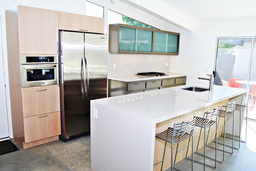 Inspiration for a mid-sized 1960s single-wall concrete floor open concept kitchen remodel in Los Angeles with an undermount sink, flat-panel cabinets, light wood cabinets, quartz countertops, beige backsplash, stone slab backsplash, stainless steel appliances and an island