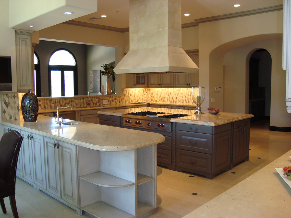 Rustik inredning av ett mellanstort kök, med en undermonterad diskho, luckor med profilerade fronter, vita skåp, granitbänkskiva, flerfärgad stänkskydd, stänkskydd i travertin, travertin golv och en köksö