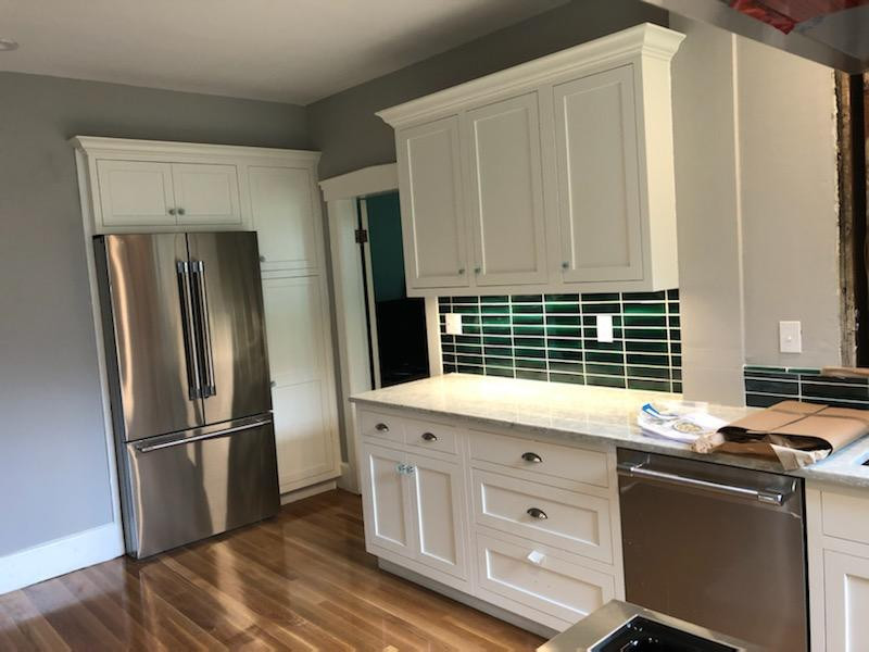 Small minimalist single-wall light wood floor and brown floor eat-in kitchen photo in Boston with an undermount sink, shaker cabinets, white cabinets, granite countertops, black backsplash, subway tile backsplash, stainless steel appliances, no island and multicolored countertops