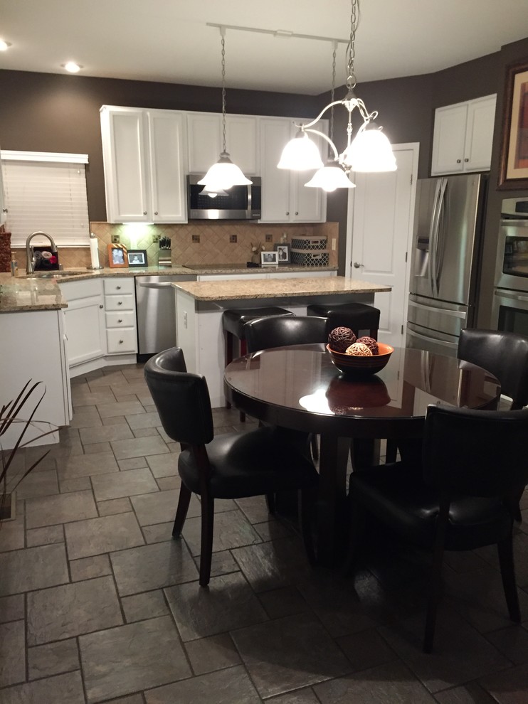 Eat-in kitchen - mid-sized traditional l-shaped gray floor eat-in kitchen idea in Cincinnati with a double-bowl sink, recessed-panel cabinets, white cabinets, granite countertops, beige backsplash, stone tile backsplash, stainless steel appliances and an island