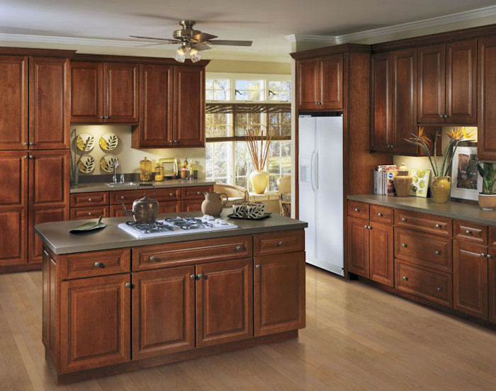 Design ideas for a large traditional l-shaped open plan kitchen in DC Metro with a submerged sink, raised-panel cabinets, medium wood cabinets, engineered stone countertops, stainless steel appliances, light hardwood flooring, an island and brown floors.