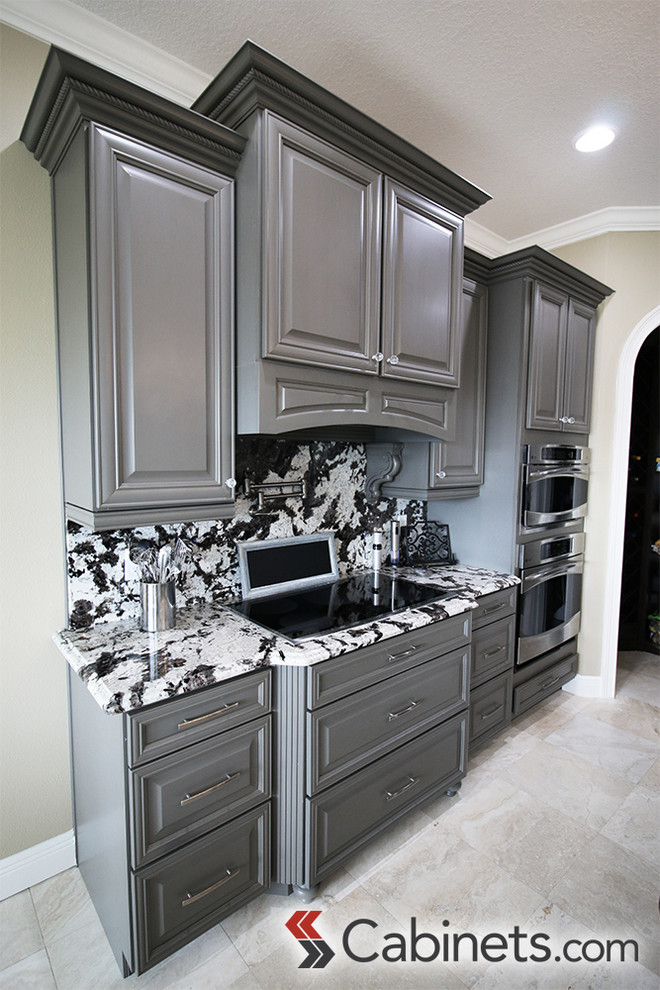 Imagen de cocina clásica renovada de tamaño medio con armarios con paneles con relieve, puertas de armario grises, electrodomésticos de acero inoxidable y una isla