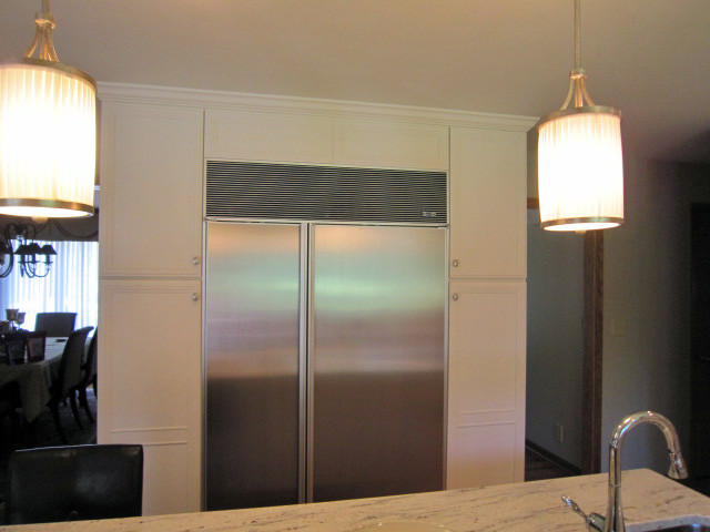 Bild på ett vintage kök och matrum, med rostfria vitvaror, vita skåp, granitbänkskiva, en köksö och luckor med infälld panel