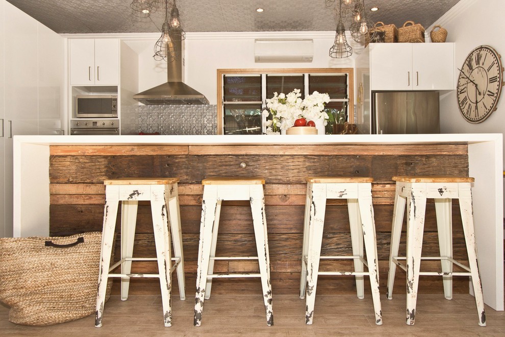 Foto på ett avskilt, mellanstort eklektiskt kök, med släta luckor, vita skåp, bänkskiva i kvarts, rostfria vitvaror, klinkergolv i keramik och en köksö