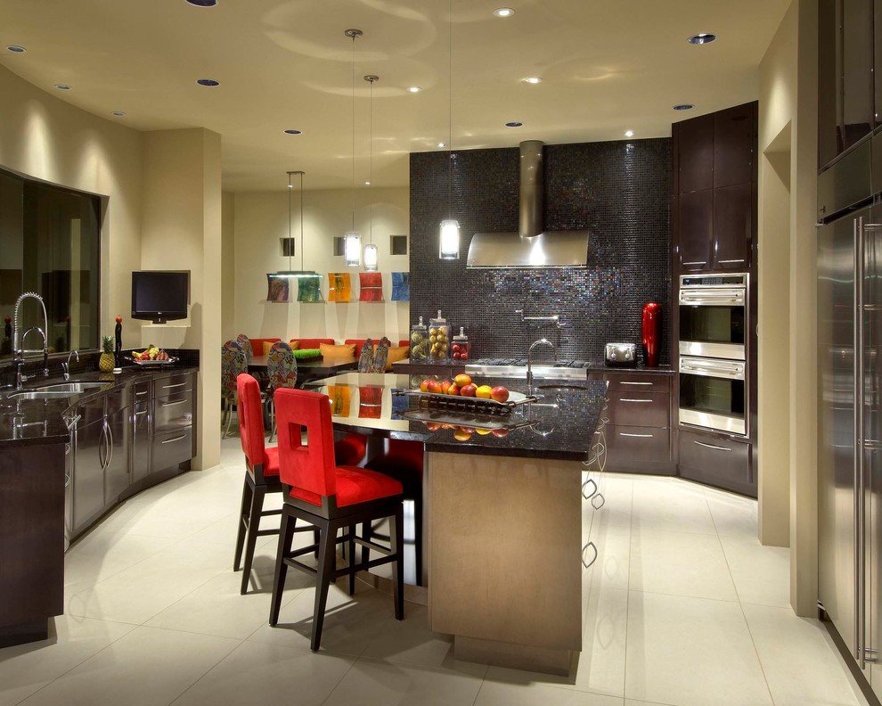 Modern inredning av ett mycket stort kök, med svart stänkskydd, glaspanel som stänkskydd, en undermonterad diskho, släta luckor, rostfria vitvaror, klinkergolv i porslin och granitbänkskiva