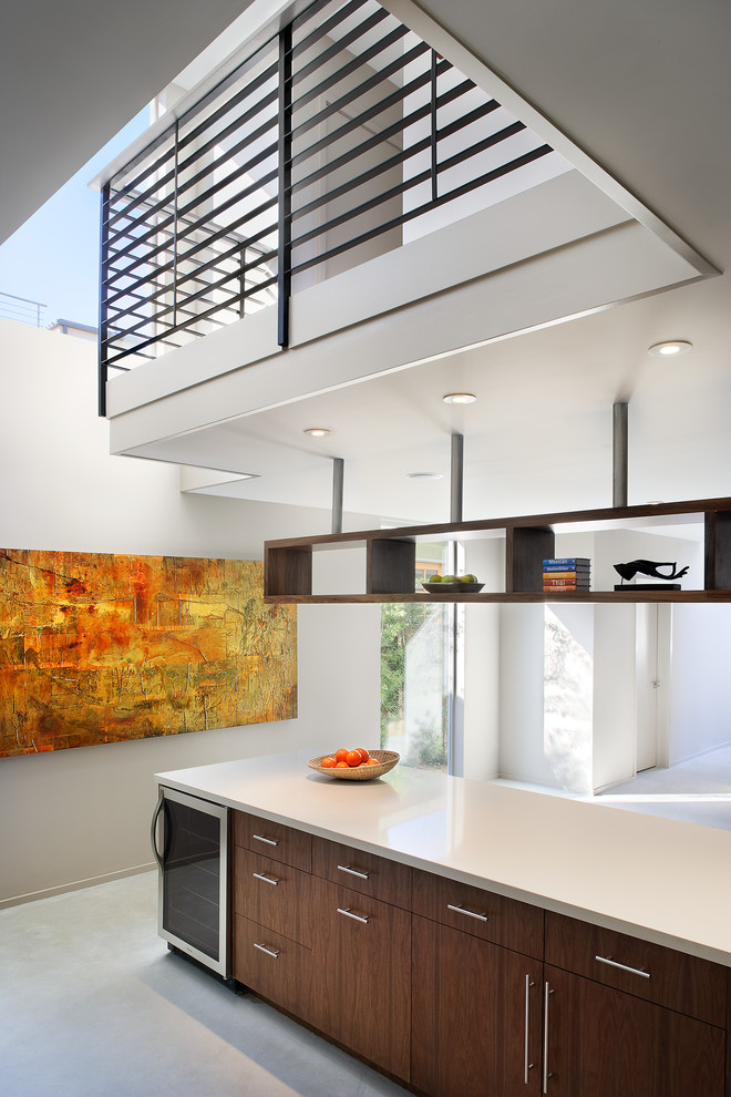 Medium sized contemporary u-shaped kitchen/diner in Los Angeles with flat-panel cabinets, medium wood cabinets, a submerged sink, engineered stone countertops, ceramic splashback, stainless steel appliances, concrete flooring and no island.