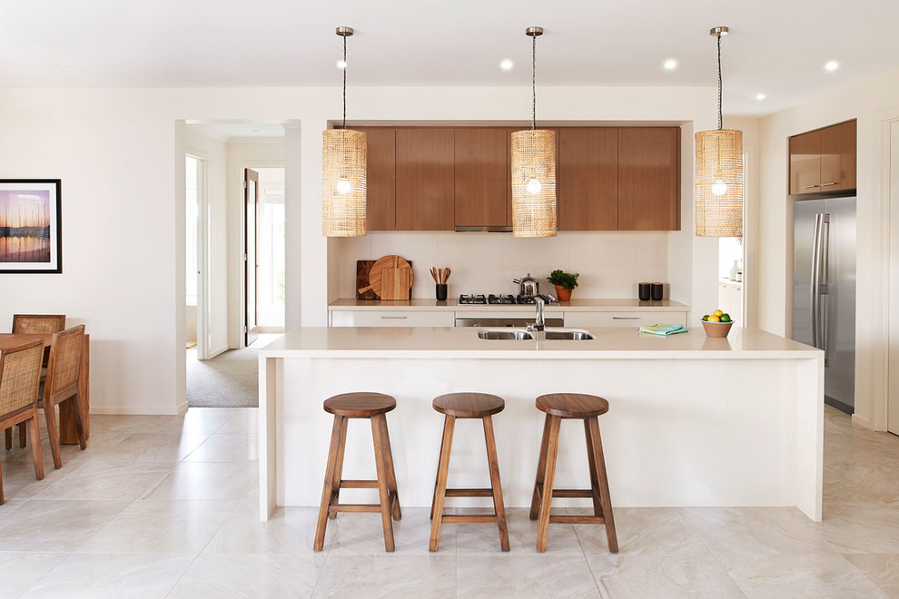 Foto di un cucina con isola centrale minimal con lavello sottopiano, ante lisce, ante in legno scuro, paraspruzzi bianco e elettrodomestici in acciaio inossidabile