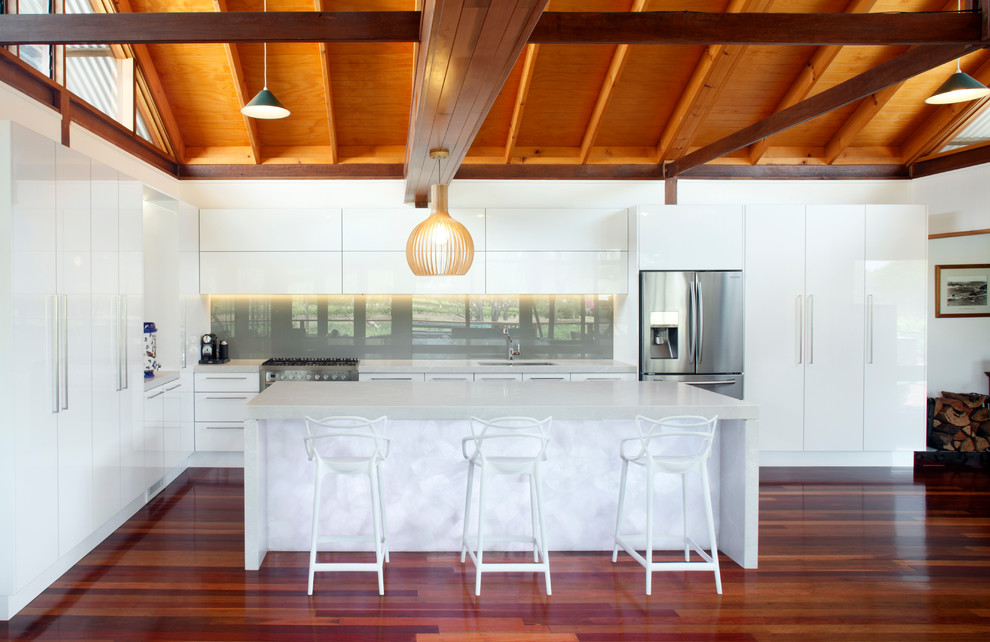 Immagine di un cucina con isola centrale design di medie dimensioni con lavello sottopiano, ante lisce, top in quarzite e pavimento in legno massello medio