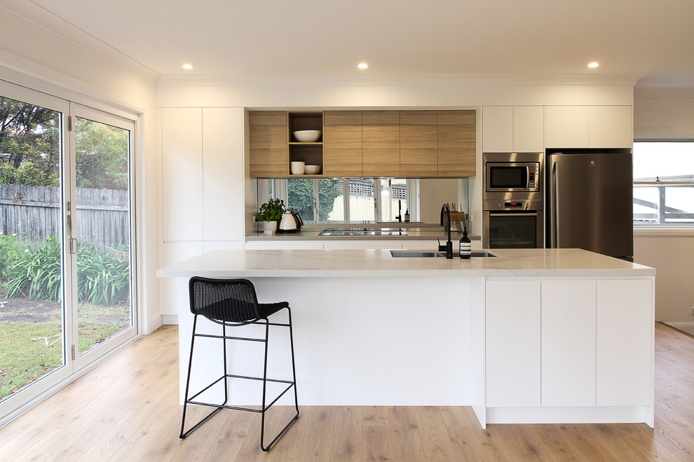 Immagine di una cucina contemporanea di medie dimensioni con lavello sottopiano, ante lisce, top in quarzite e pavimento in legno massello medio