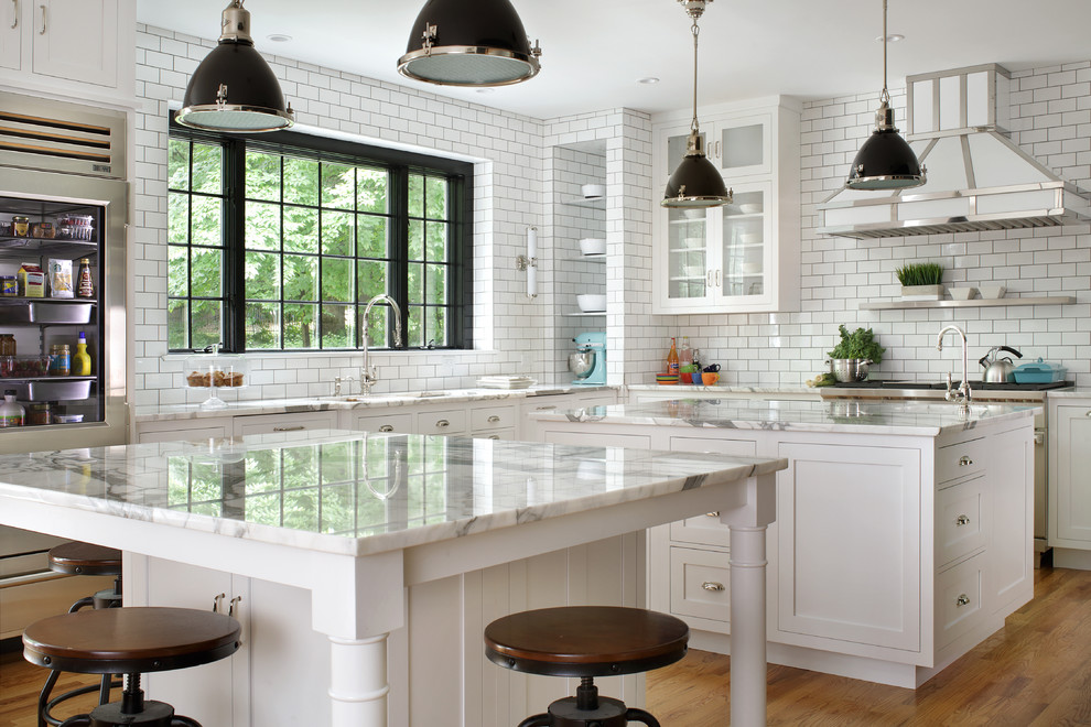 Kitchen - large transitional l-shaped light wood floor kitchen idea in New York with an undermount sink, shaker cabinets, white cabinets, marble countertops, white backsplash, subway tile backsplash, stainless steel appliances, two islands and white countertops