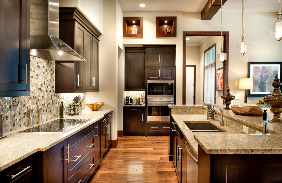 Inspiration for a transitional u-shaped medium tone wood floor kitchen remodel in Orlando with a double-bowl sink, shaker cabinets, dark wood cabinets, multicolored backsplash, stainless steel appliances and an island