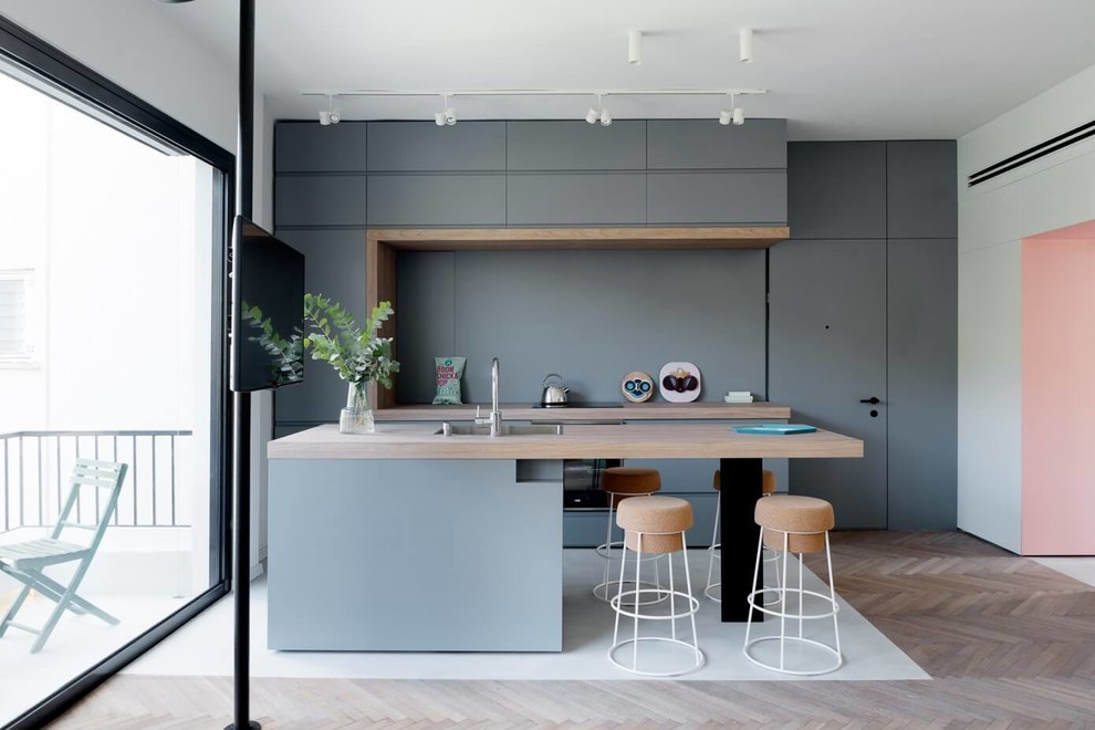 Foto di una cucina contemporanea con lavello da incasso, ante lisce, ante grigie, top in legno, elettrodomestici in acciaio inossidabile e parquet chiaro