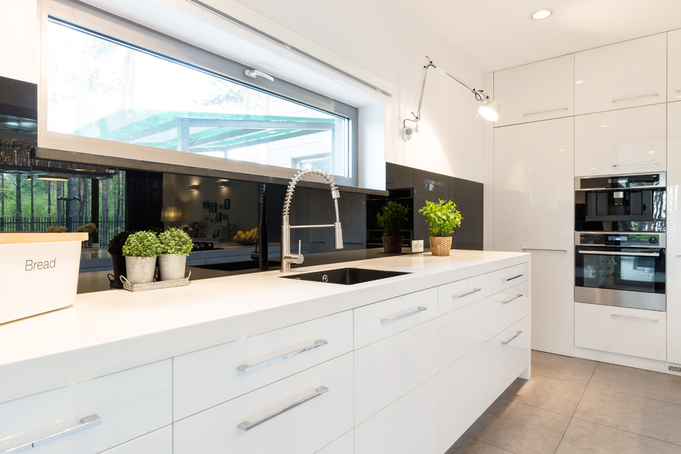 Idéer för att renovera ett stort funkis vit vitt kök, med en undermonterad diskho, vita skåp, svart stänkskydd, klinkergolv i keramik, en köksö och grått golv
