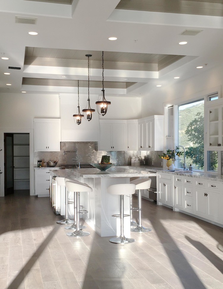 Modern inredning av ett mellanstort kök, med en dubbel diskho, luckor med upphöjd panel, vita skåp, granitbänkskiva, vitt stänkskydd, stänkskydd i mosaik, rostfria vitvaror, mellanmörkt trägolv och en köksö