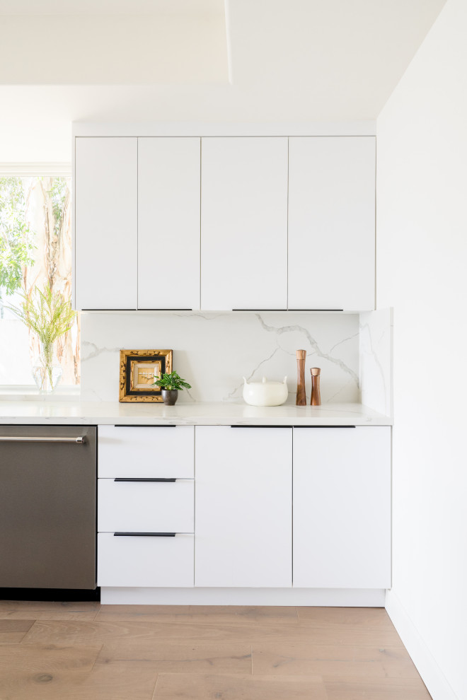 Foto di una grande cucina moderna con ante lisce, ante bianche, paraspruzzi in marmo, elettrodomestici in acciaio inossidabile, pavimento in legno massello medio, pavimento marrone e top bianco