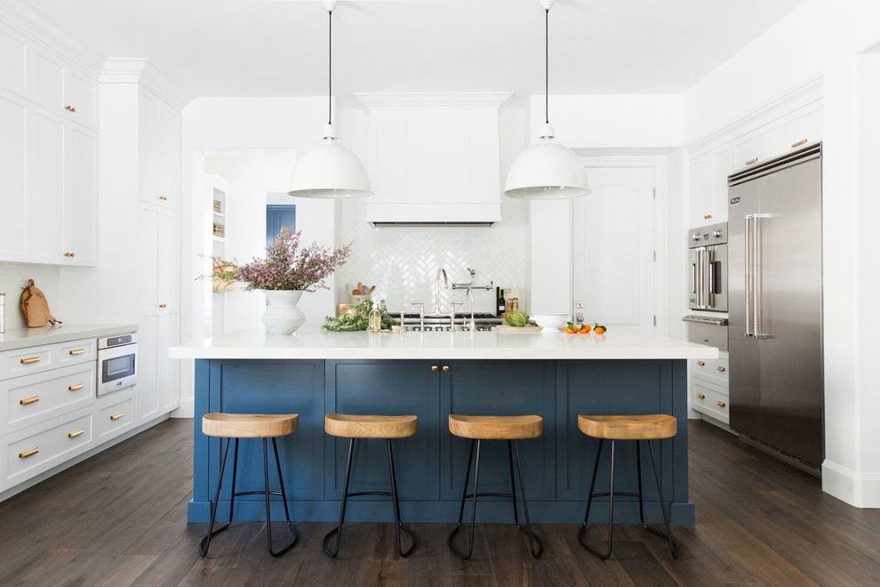 Large traditional u-shaped kitchen in Salt Lake City with shaker cabinets, blue cabinets, white splashback, stainless steel appliances, dark hardwood flooring, an island, white worktops and brown floors.