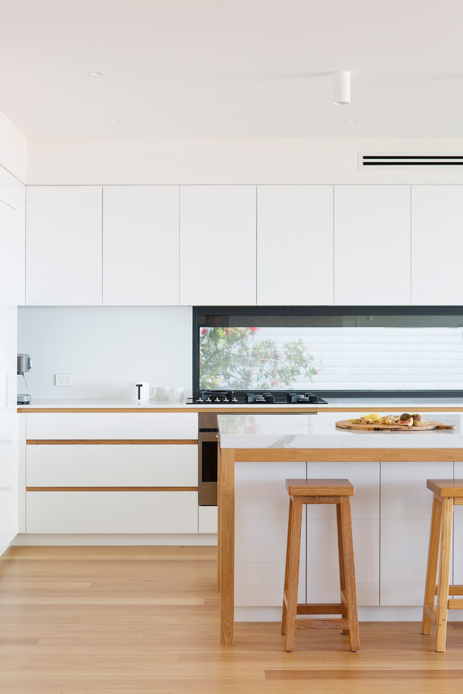 Cette image montre une cuisine américaine minimaliste avec un plan de travail en quartz modifié et un plan de travail blanc.