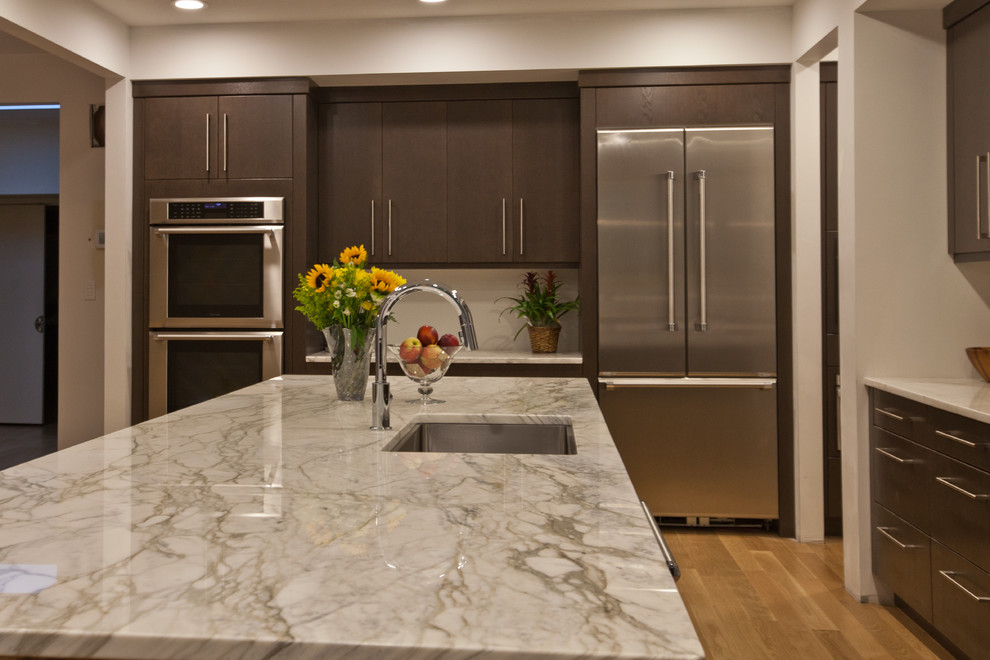 Example of a huge trendy l-shaped light wood floor eat-in kitchen design in Raleigh with a single-bowl sink, flat-panel cabinets, dark wood cabinets, marble countertops, white backsplash, stainless steel appliances and an island