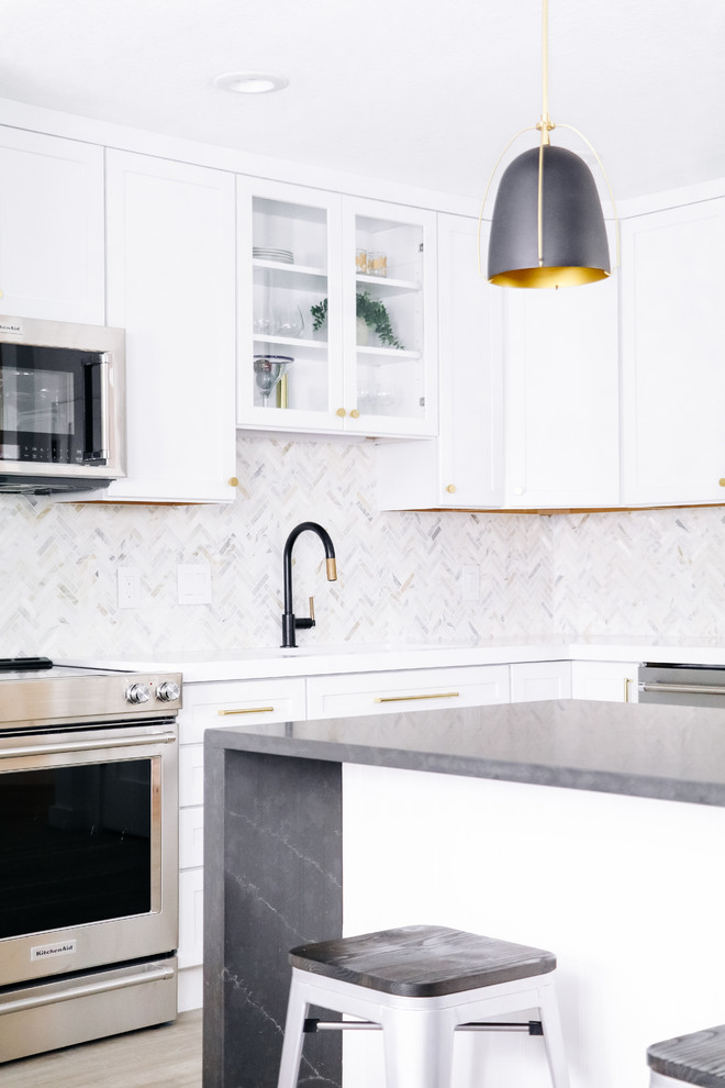 Modern inredning av ett mellanstort vit vitt kök, med en undermonterad diskho, luckor med infälld panel, vita skåp, bänkskiva i kvarts, vitt stänkskydd, stänkskydd i marmor, rostfria vitvaror, ljust trägolv, en köksö och beiget golv