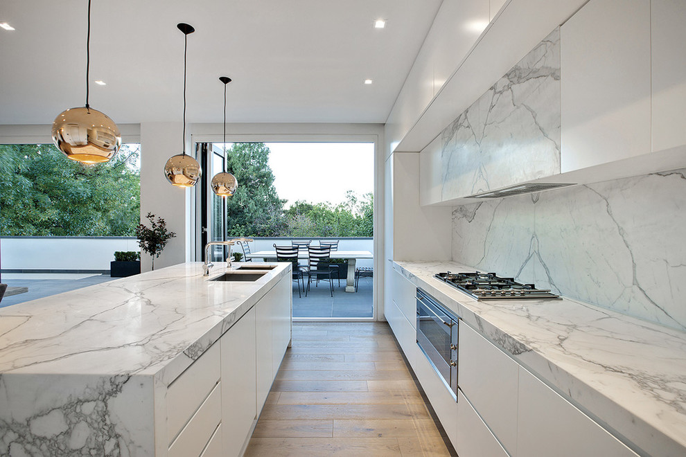 Foto de cocina minimalista grande con fregadero bajoencimera, encimera de mármol, salpicadero blanco, salpicadero de losas de piedra y una isla