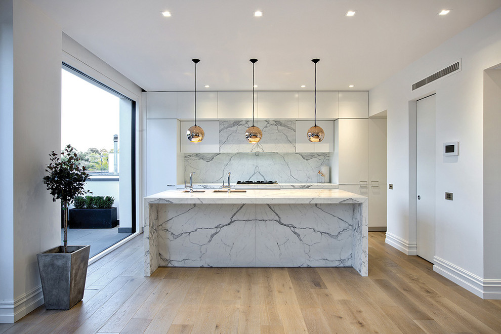 Modern inredning av ett stort kök, med en undermonterad diskho, marmorbänkskiva, vitt stänkskydd, stänkskydd i sten och en köksö